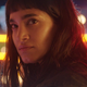Sofia Boutella, wearing short bangs and with bright lights behind her, in a scene from Prisoners of the Ghostland.